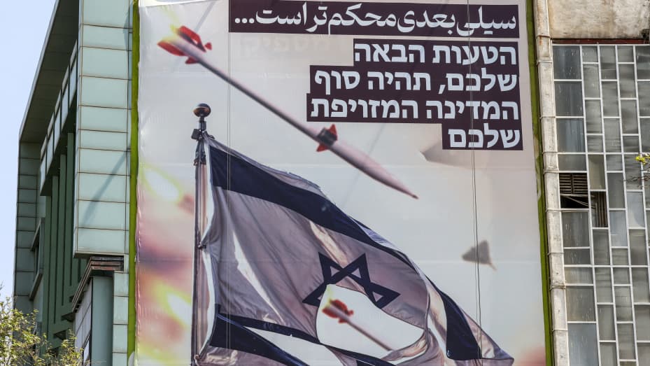 TOPSHOT - Una pancarta que muestra misiles y drones volando junto a una bandera israelí rota, con un texto en persa que dice "la próxima bofetada será más dura" y en hebreo "tu próximo error será el fin de tu falso estado", cuelga en la fachada de un edificio en la Plaza Palestina en Teherán el 14 de abril de 2024. El 14 de abril, Irán instó a Israel a no tomar represalias militares por un ataque sin precedentes ocurrido durante la noche, que Teherán presentó como una respuesta justificada a un ataque mortal contra el edificio de su consulado en Damasco. (Foto por ATTA K