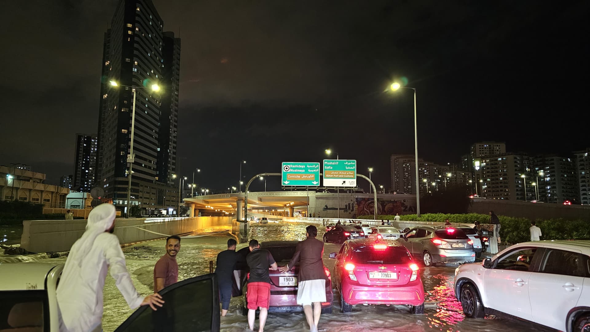 People wade through submerged street after heavy rain in United Arab Emirates on April 16, 2024. 