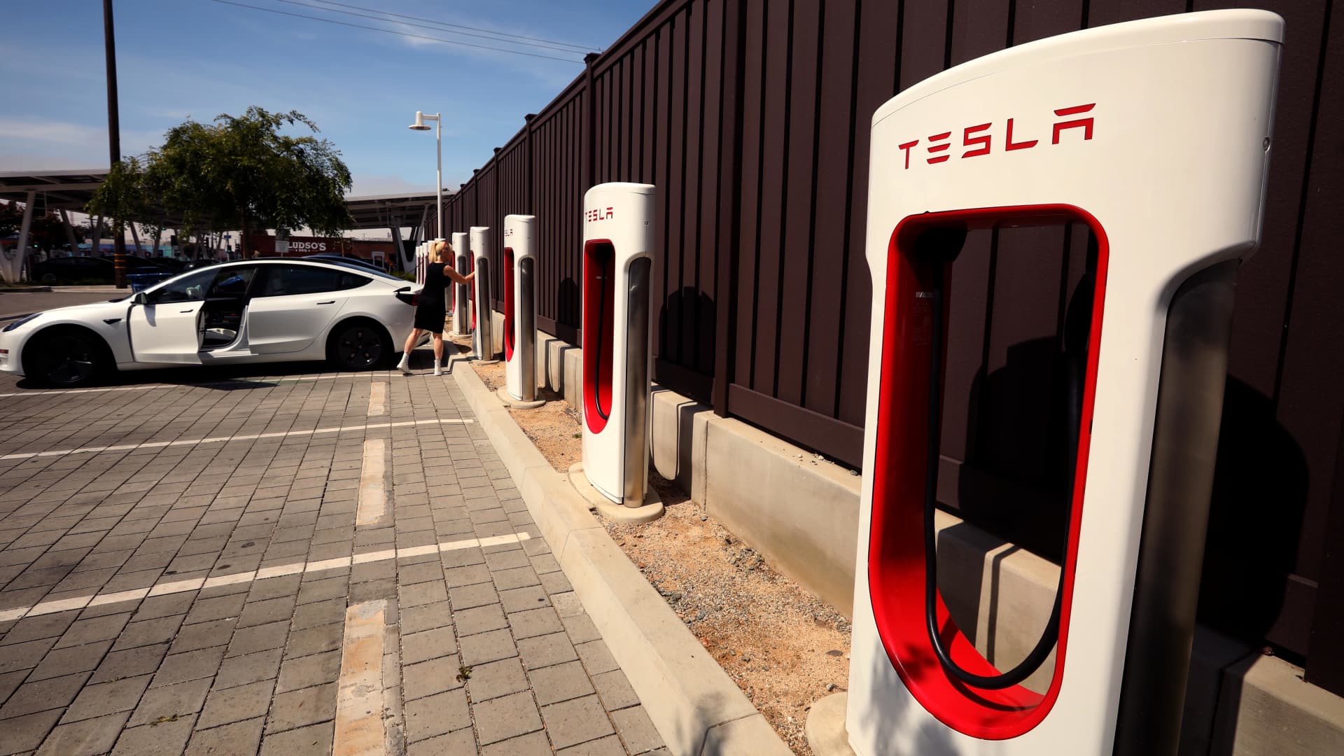 A woman prepares to unplug her Tesla at a Tesla Supercharger station at the corner of 14th St. and Santa Monica Blvd. in Santa Monica on April 17, 2024. 