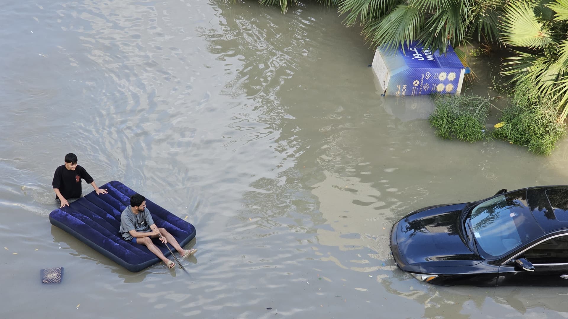 Two men use an inflatable bed to float above the water as downpour causes heavy flooding in Dubai, United Arab Emirates on April 17, 2024.