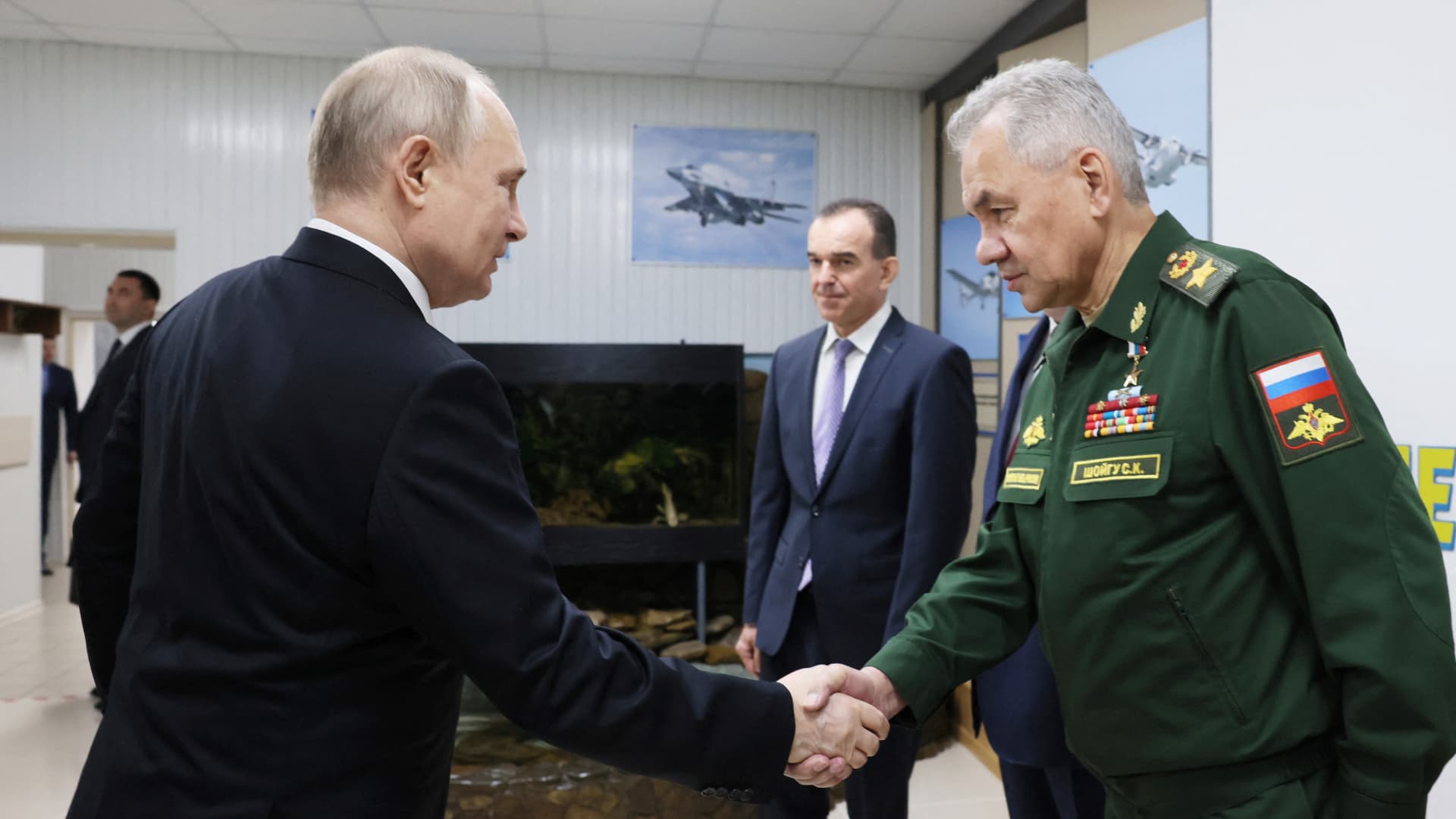 In this pool photograph distributed by Russian state owned agency Russian President Vladimir Putin (L) shakes hands with Russia's Defence Minister Sergei Shoigu during a visit at the Krasnodar Higher Military Aviation School of Pilots in Krasnodar on March 7, 2024.