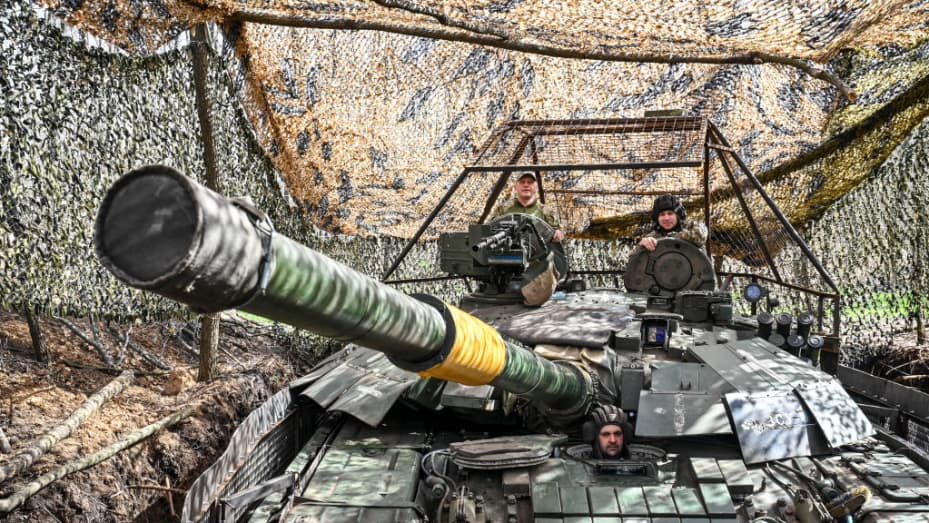 Tres militares permanecen en un tanque de la 1.ª Brigada de Tanques de las Fuerzas Terrestres de Ucrania, ocultos por redes de camuflaje en Ucrania, el 31 de marzo de 2024. (Foto de Ukrinform/NurPhoto vía Getty Images)