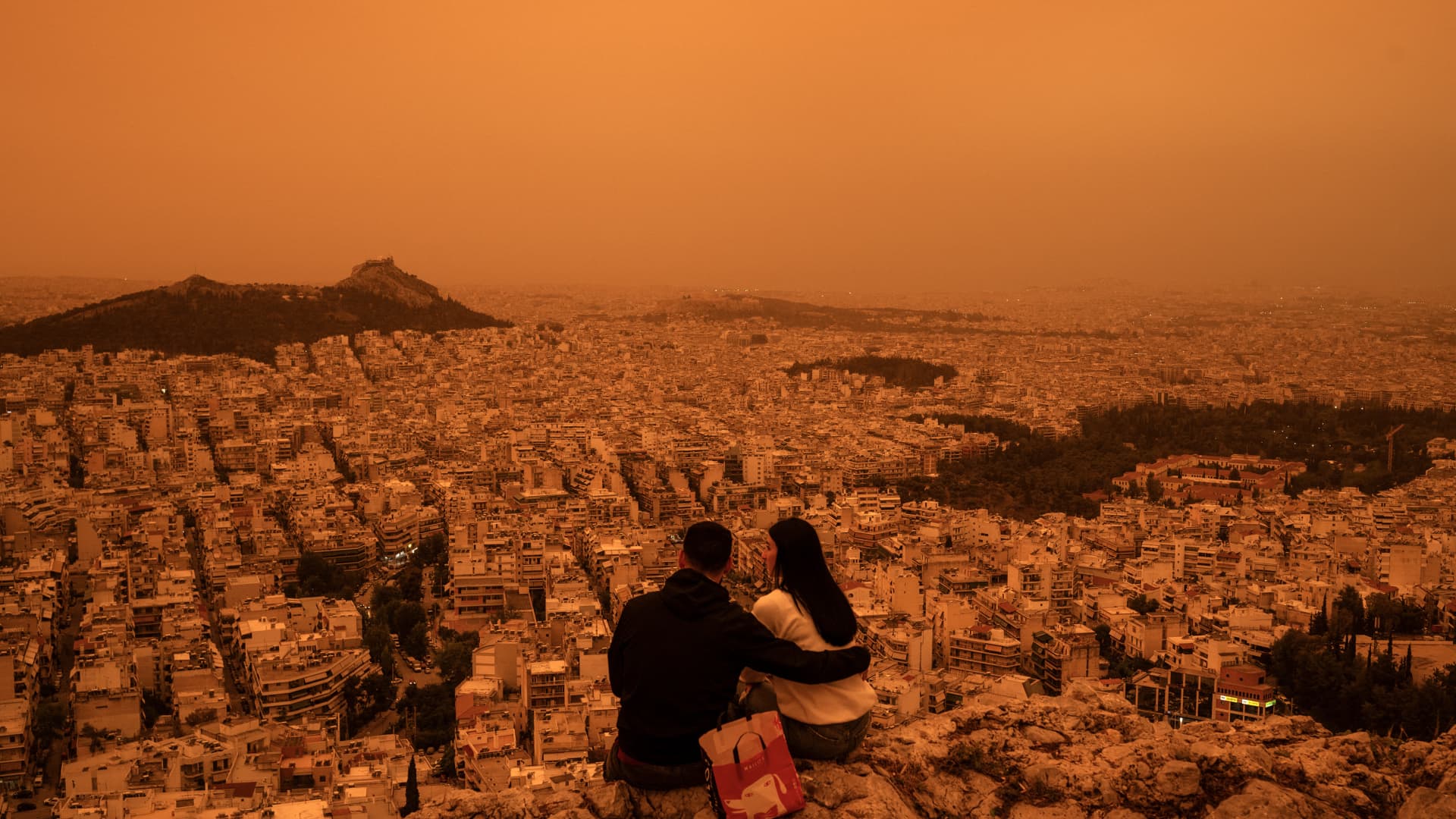 A couple sits on Tourkovounia hill, as southerly winds carry waves of Saharan dust, in Athens, on April 23, 2024.