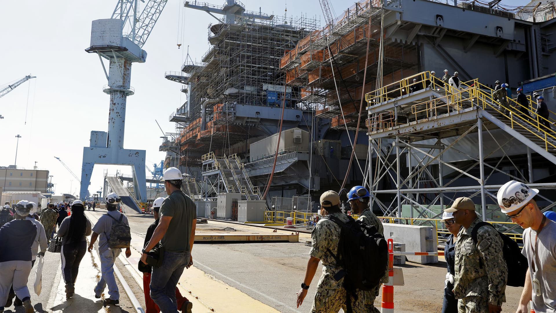 Newport News Shipbuilding workers and Navy sailors walk past the USS George Washington as it rests pier side Oct. 11, 2019. 