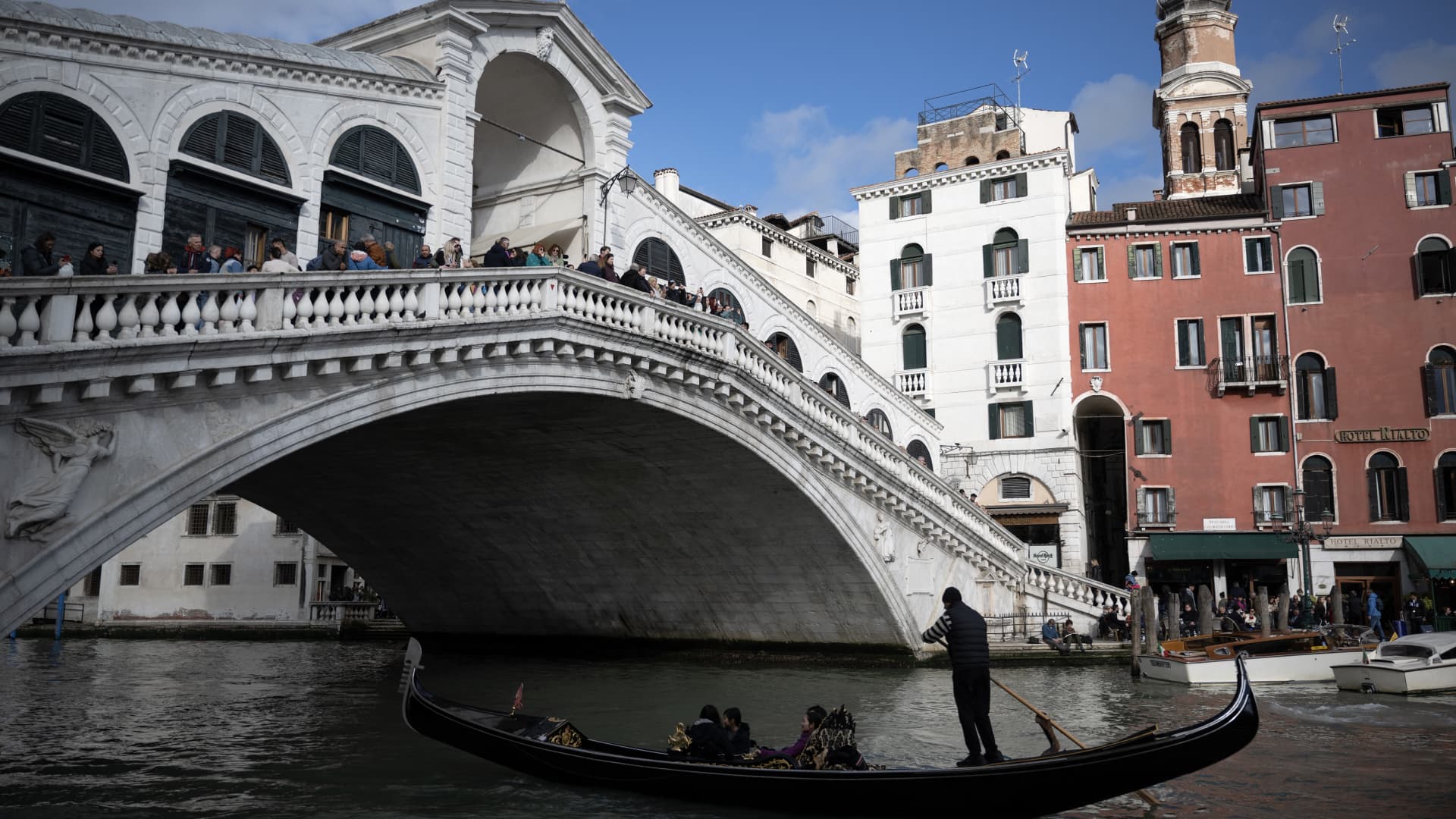 A gondola sails under the Rialto Bridge on April 24, 2024 in Venice, on the eve of the start of the official trial of the city's booking system for day-trippers. Venice will begin on April 25, 2024 charging day trippers for entry, a world first aimed at easing pressure on the Italian city drowning under the weight of mass tourism.
