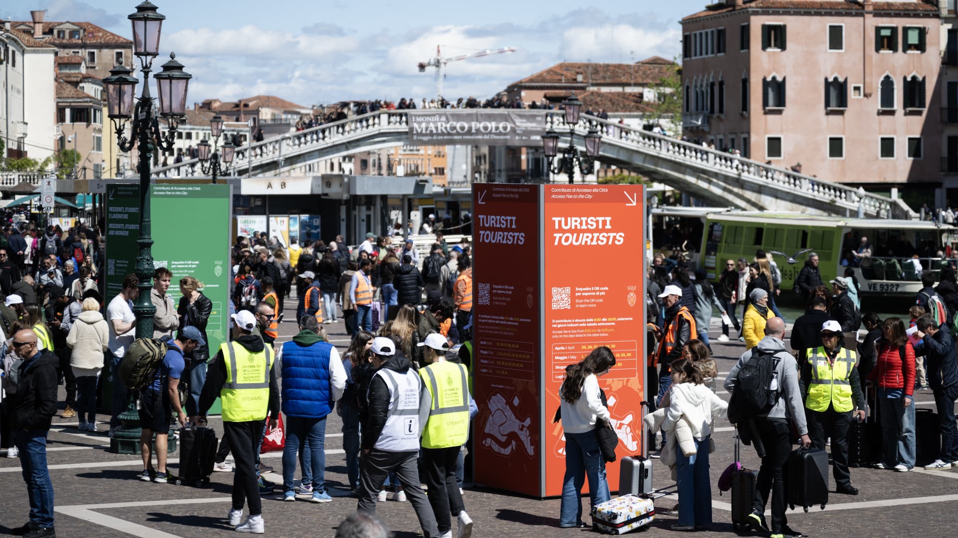 Tourists stand in front of Santa Lucia train station in Venice as they wait to pass controls and buy the five-euro ticket to enter the historic city center on April 25, 2024.