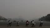 Cyclists and bikers stop at a traffic light, as buildings are faintly seen, rear, shrouded in a haze of smog in Beijing. (AP Photo/Shuji Kajiyama)