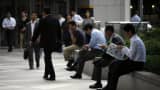 Japanese office workers rest at a business district in Tokyo.